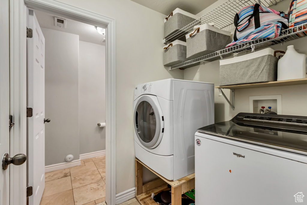 Clothes washing area featuring washing machine and clothes dryer, baseboards, and laundry area