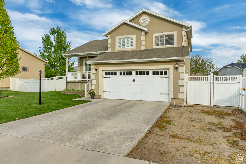 View of front of home featuring a gate, stucco siding, a front lawn, and a garage