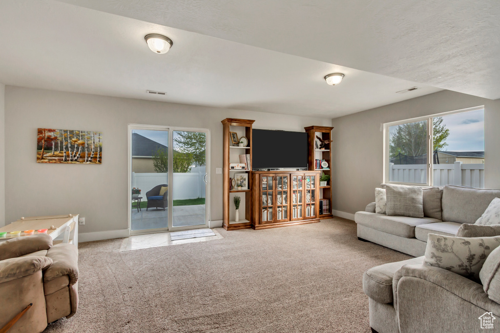 Carpeted living room with a wealth of natural light, visible vents, and baseboards