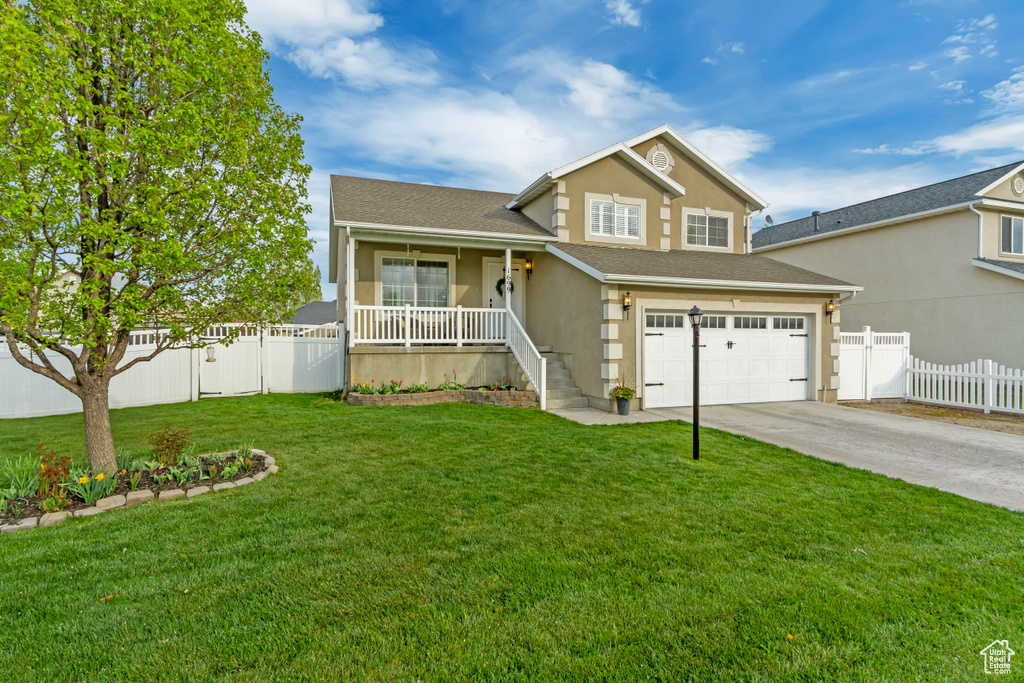 View of front facade featuring concrete driveway, covered porch, an attached garage, fence, and stucco siding