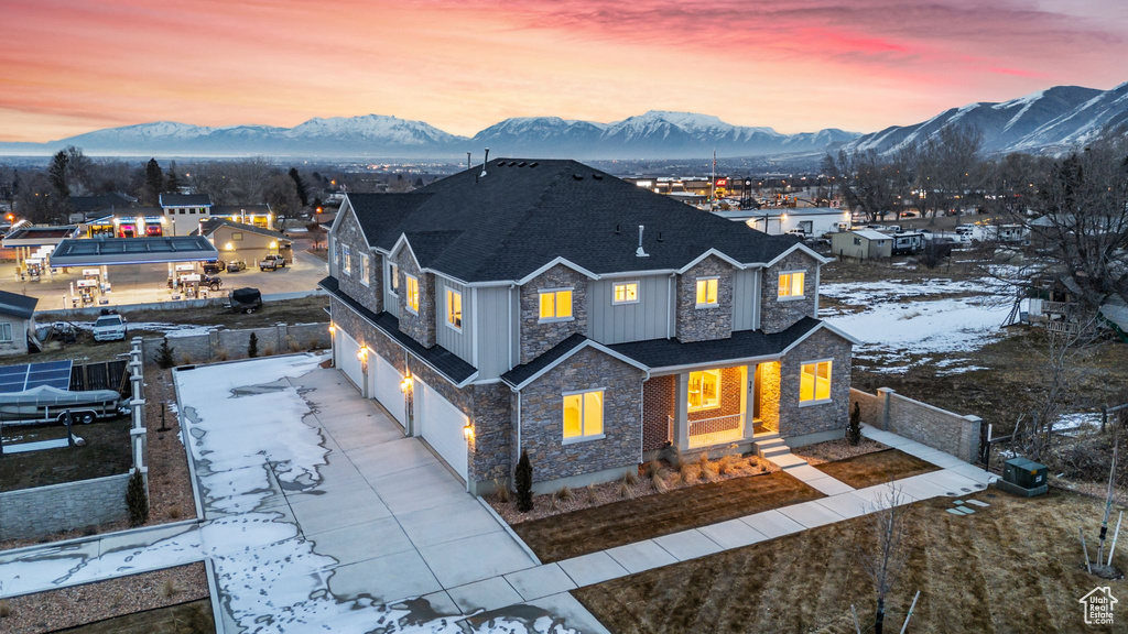 View of front of property featuring a garage, a mountain view, fence, and stone siding