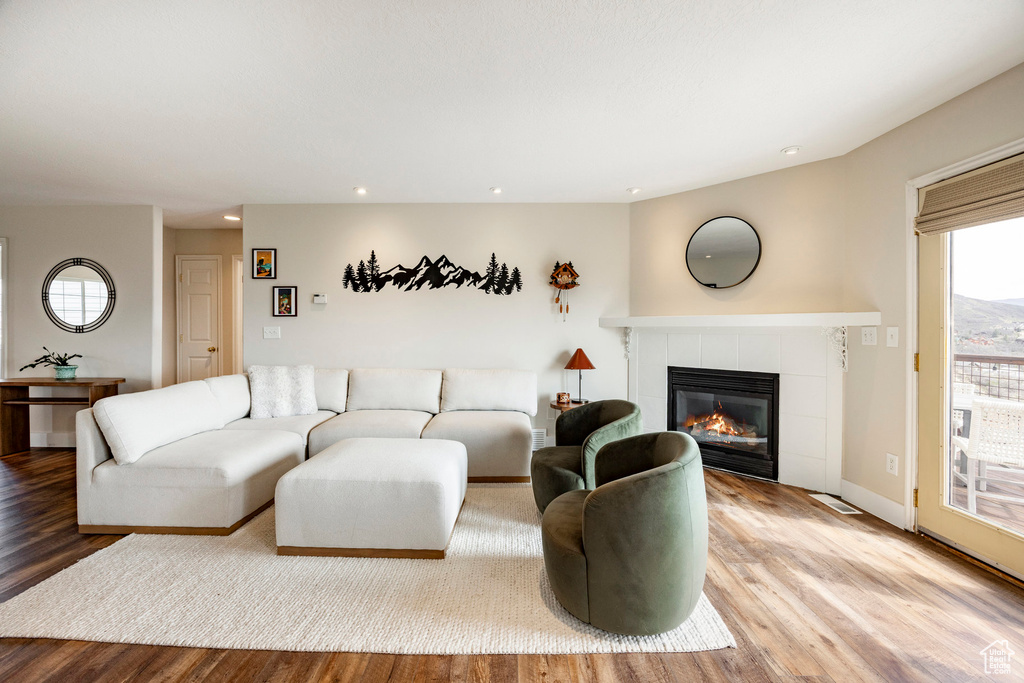 Living area with a tile fireplace, wood finished floors, recessed lighting, and baseboards