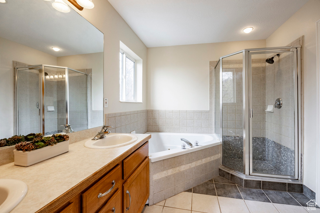 Bathroom featuring tile patterned floors, double vanity, a shower stall, and a garden tub
