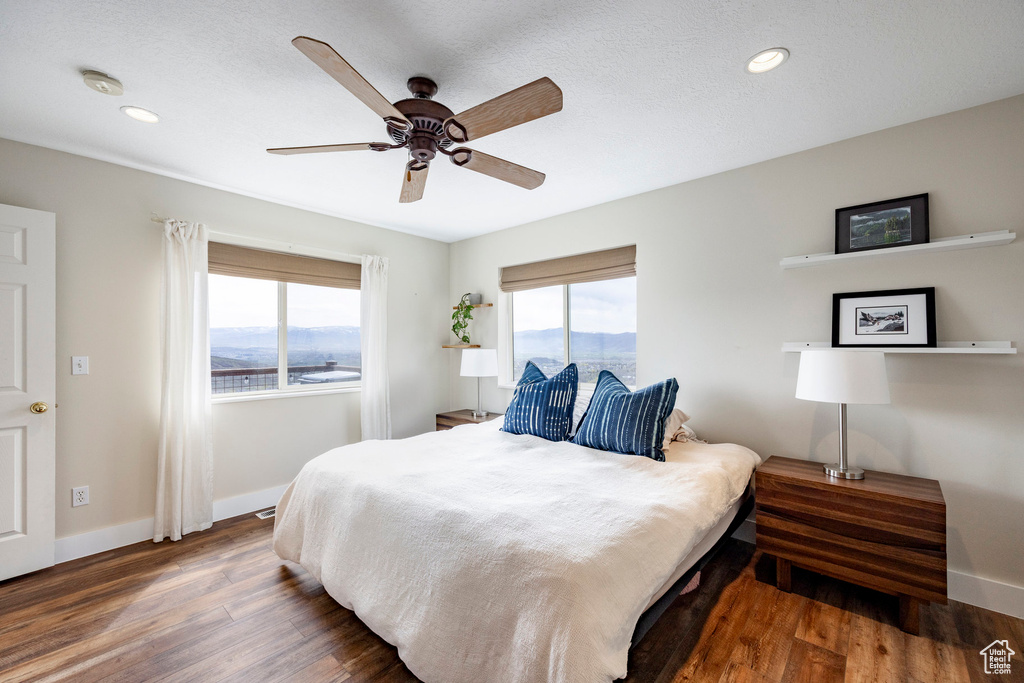 Bedroom featuring multiple windows, baseboards, wood finished floors, recessed lighting, and a ceiling fan