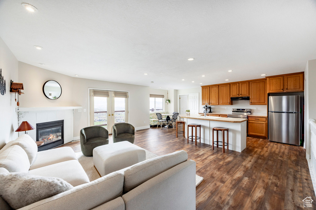 Living room featuring dark wood finished floors, recessed lighting, a fireplace, french doors, and baseboards