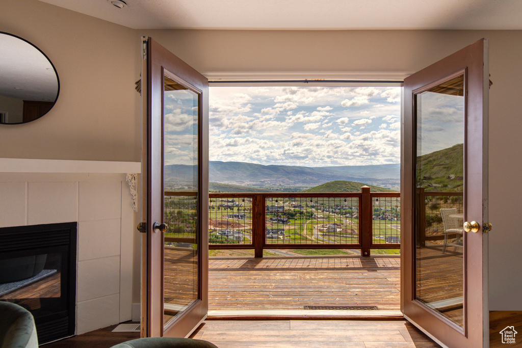 Doorway featuring french doors, a mountain view, wood finished floors, and a tiled fireplace