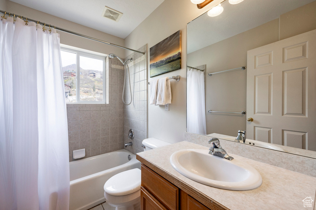Bathroom with toilet, vanity, and shower / bath combo with shower curtain