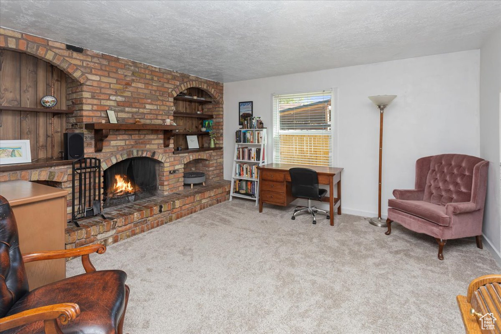 Carpeted living room featuring a brick fireplace, a textured ceiling, and baseboards