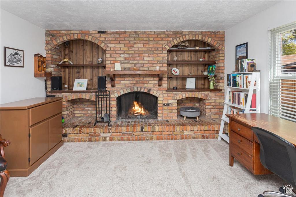 Living room with a brick fireplace, a textured ceiling, and carpet flooring