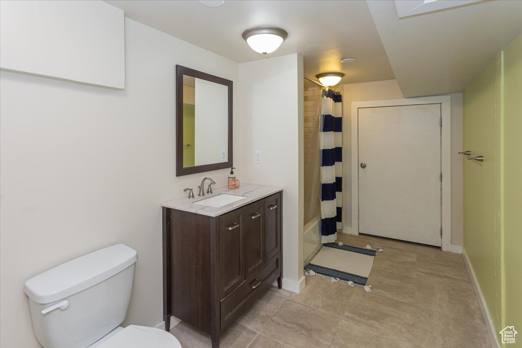 Bathroom featuring baseboards, shower / bathtub combination with curtain, toilet, and vanity