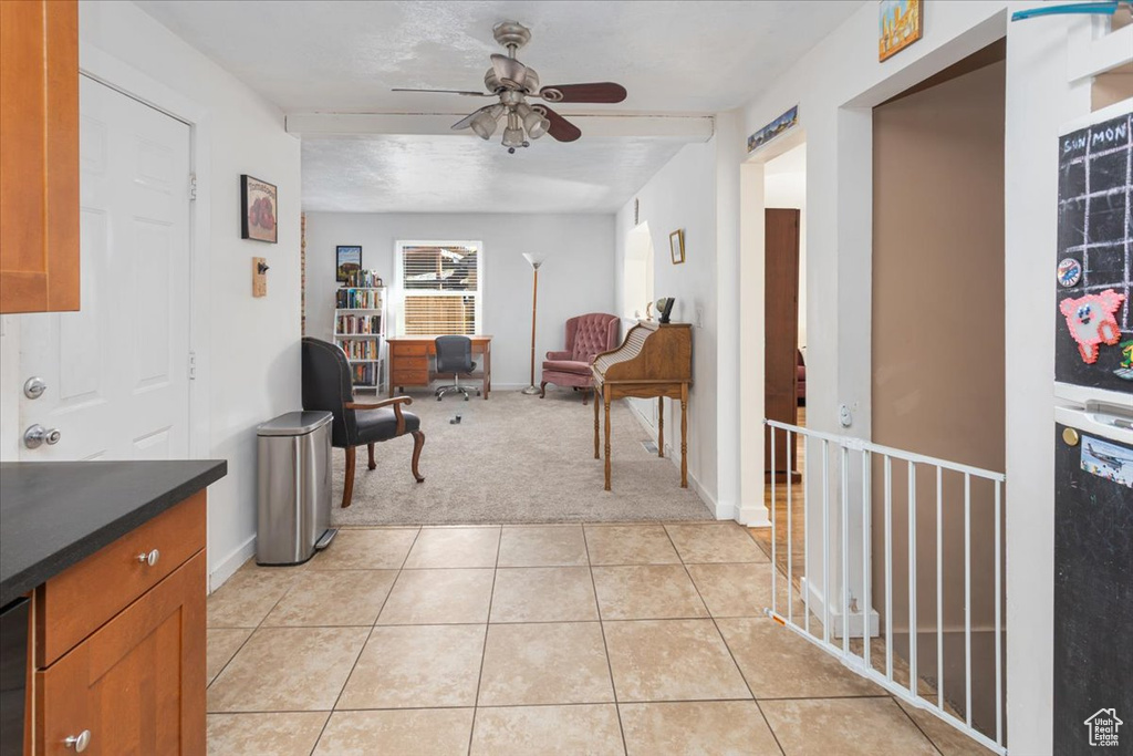 Interior space featuring light tile patterned floors, a ceiling fan, baseboards, and light carpet