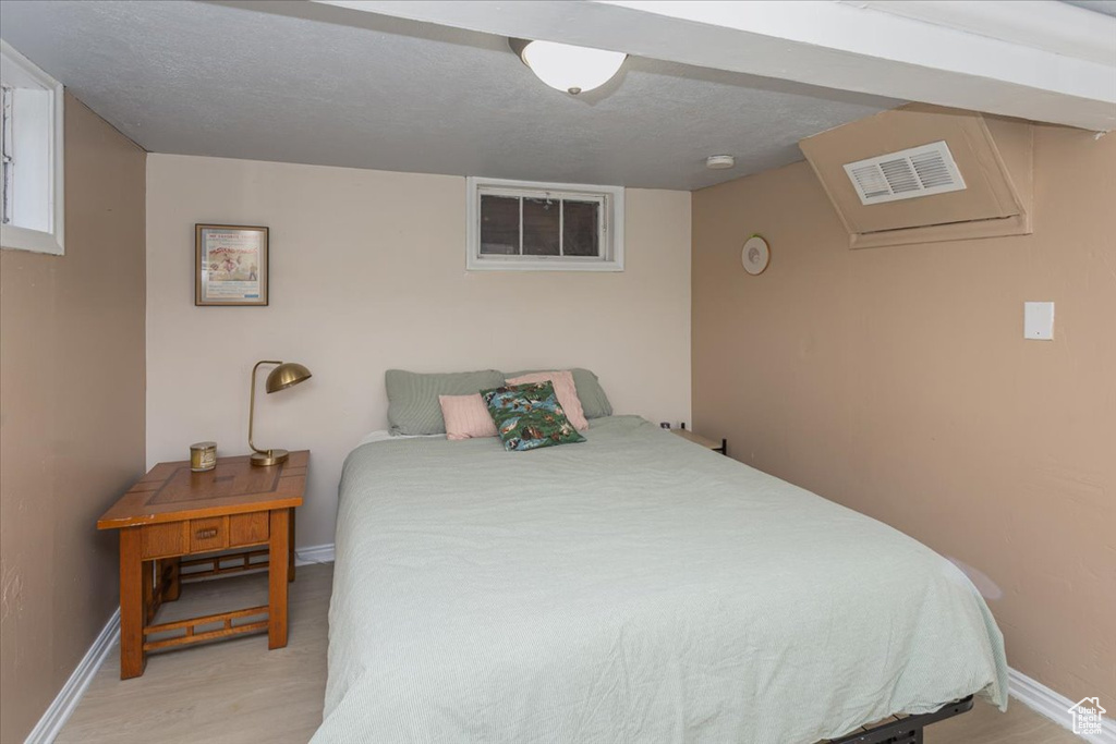 Bedroom featuring visible vents, light wood-style flooring, and baseboards