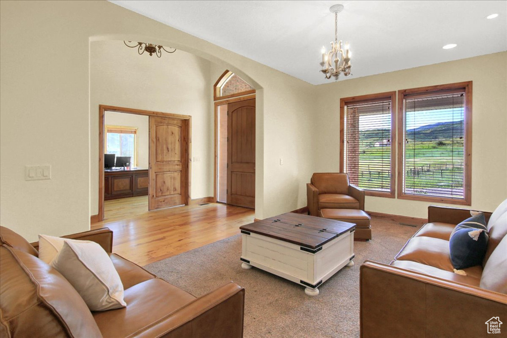 Living room with a chandelier, light wood-type flooring, arched walkways, and plenty of natural light