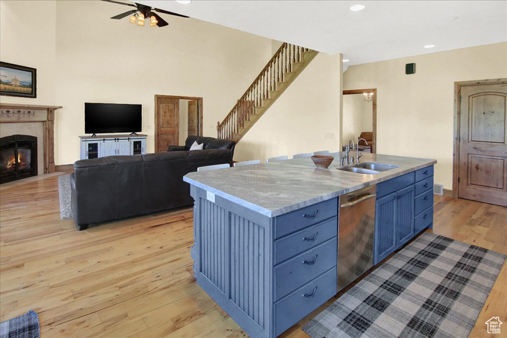 Kitchen featuring a sink, a ceiling fan, light wood-style flooring, stainless steel dishwasher, and blue cabinets