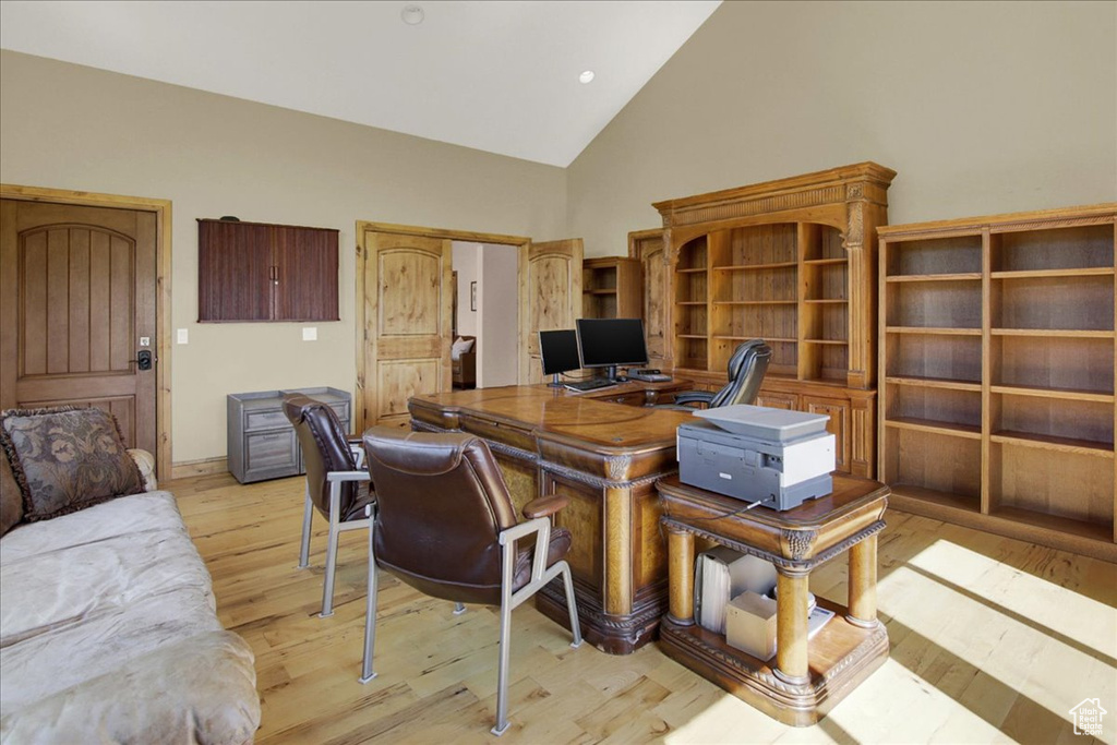 Office with light wood-style flooring and high vaulted ceiling