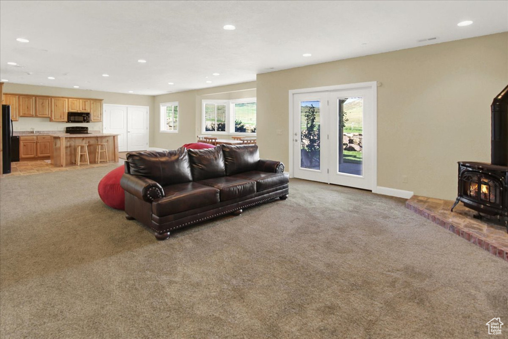 Living room featuring baseboards, a wood stove, light carpet, and recessed lighting