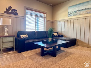 Carpeted living area featuring a decorative wall and wainscoting