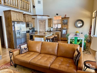 Living room featuring light wood-type flooring, visible vents, and a towering ceiling