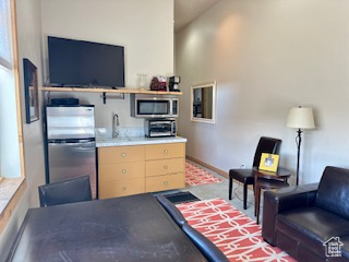 Kitchen with a toaster, light countertops, light brown cabinets, a sink, and appliances with stainless steel finishes