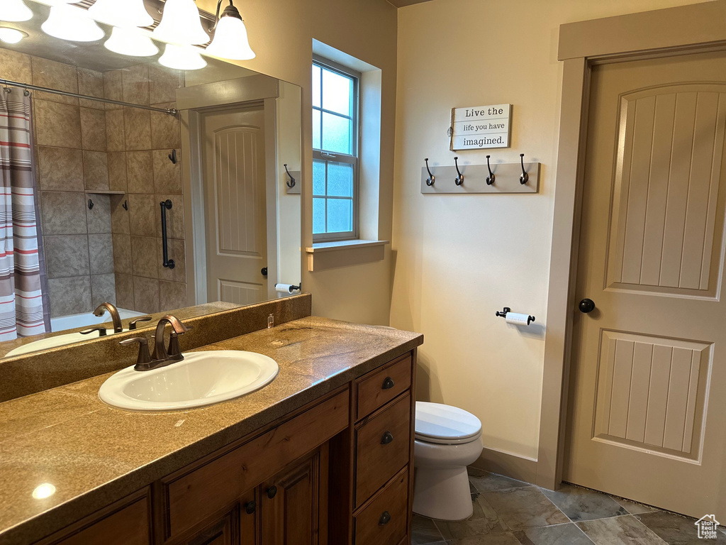 Full bath with tiled shower, toilet, and vanity