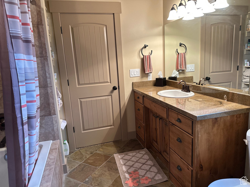 Bathroom with vanity, tiled shower / bath combo, and a chandelier