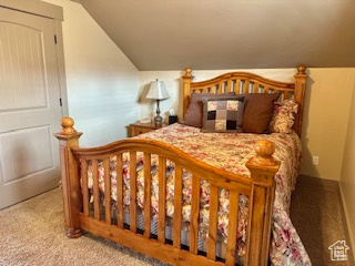 Bedroom featuring lofted ceiling, carpet flooring, and baseboards