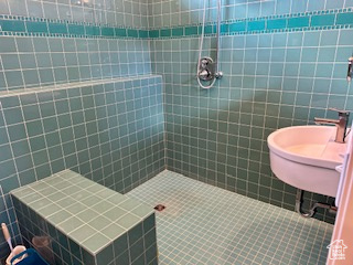 Bathroom with a tile shower, tile walls, and a sink