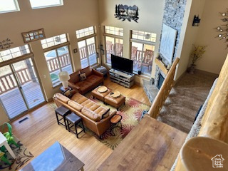 Living room featuring wood finished floors, a towering ceiling, and a stone fireplace