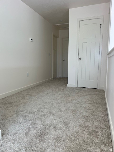 Carpeted spare room with baseboards and attic access