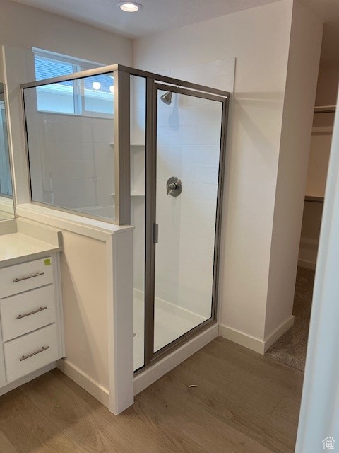 Full bathroom featuring vanity, a shower stall, wood finished floors, and baseboards