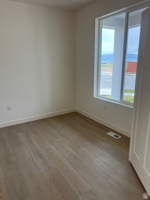 Unfurnished room featuring visible vents, wood finished floors, and baseboards