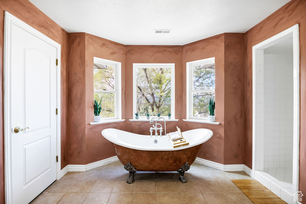 Full bathroom featuring visible vents, a freestanding tub, tile patterned floors, and baseboards