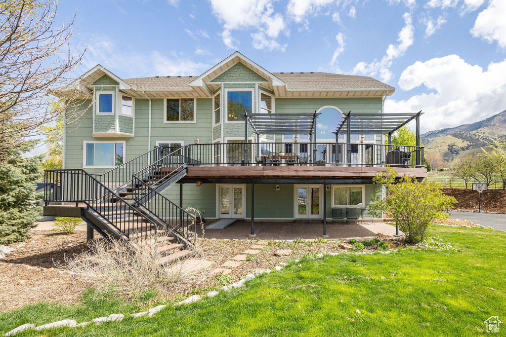 Back of property with a pergola, stairway, a yard, a deck with mountain view, and french doors