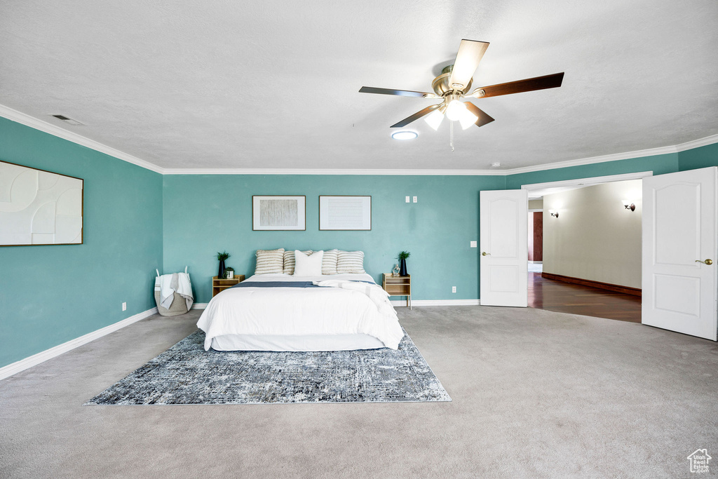 Carpeted bedroom with ornamental molding, a ceiling fan, visible vents, and baseboards