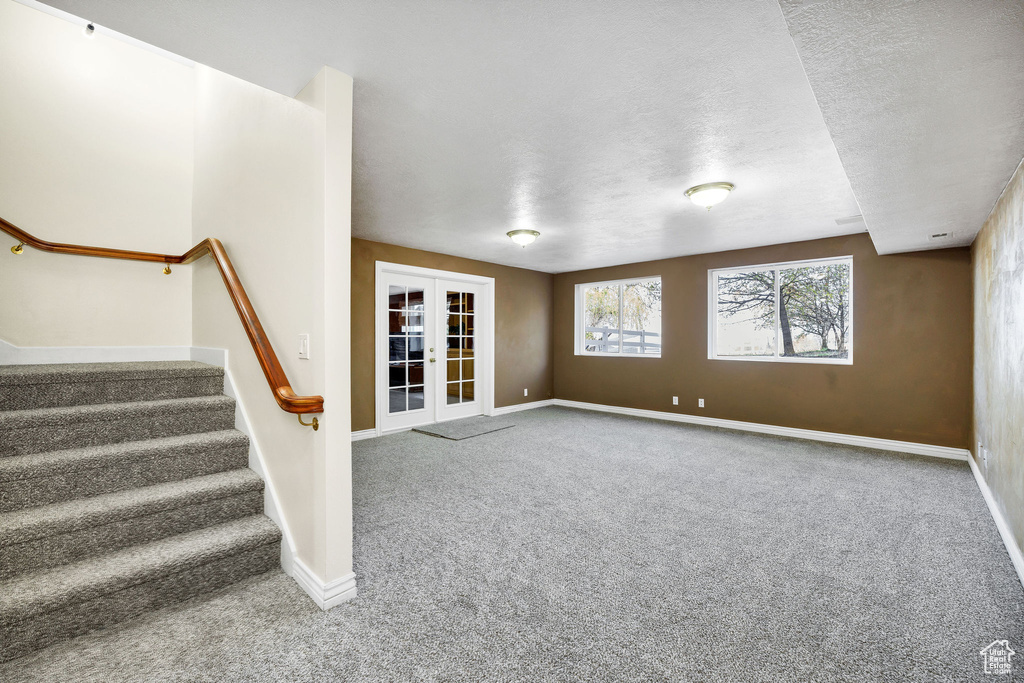 Unfurnished living room featuring french doors, baseboards, and carpet floors