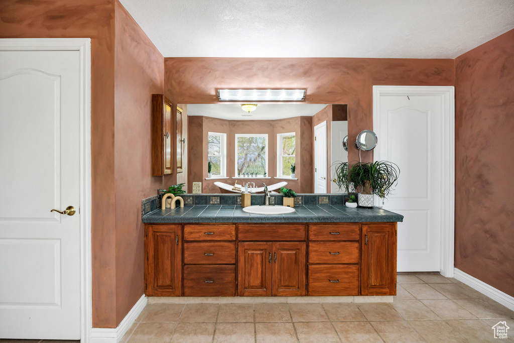 Bathroom with baseboards, tile patterned floors, and vanity