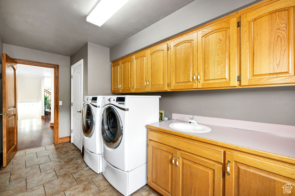 Washroom featuring independent washer and dryer, cabinet space, and a sink