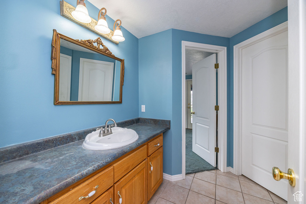 Bathroom with vanity, tile patterned floors, and baseboards