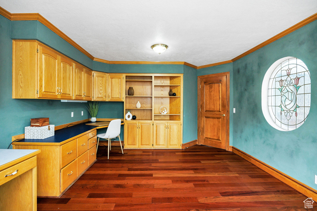 Office featuring crown molding, dark wood-style floors, built in desk, and baseboards
