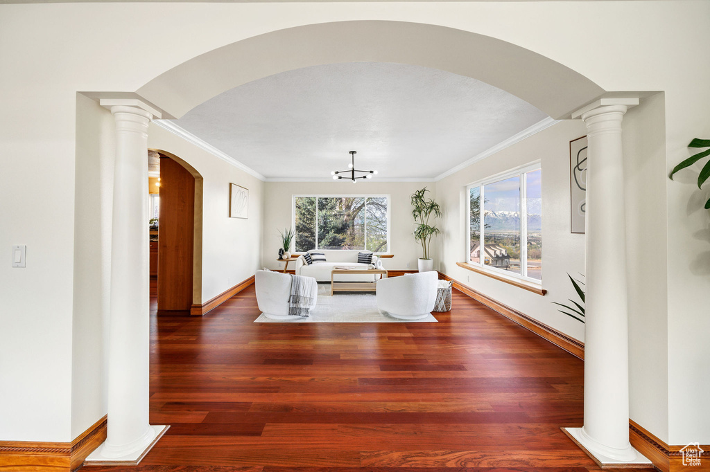 Living area with crown molding, arched walkways, wood finished floors, and baseboards