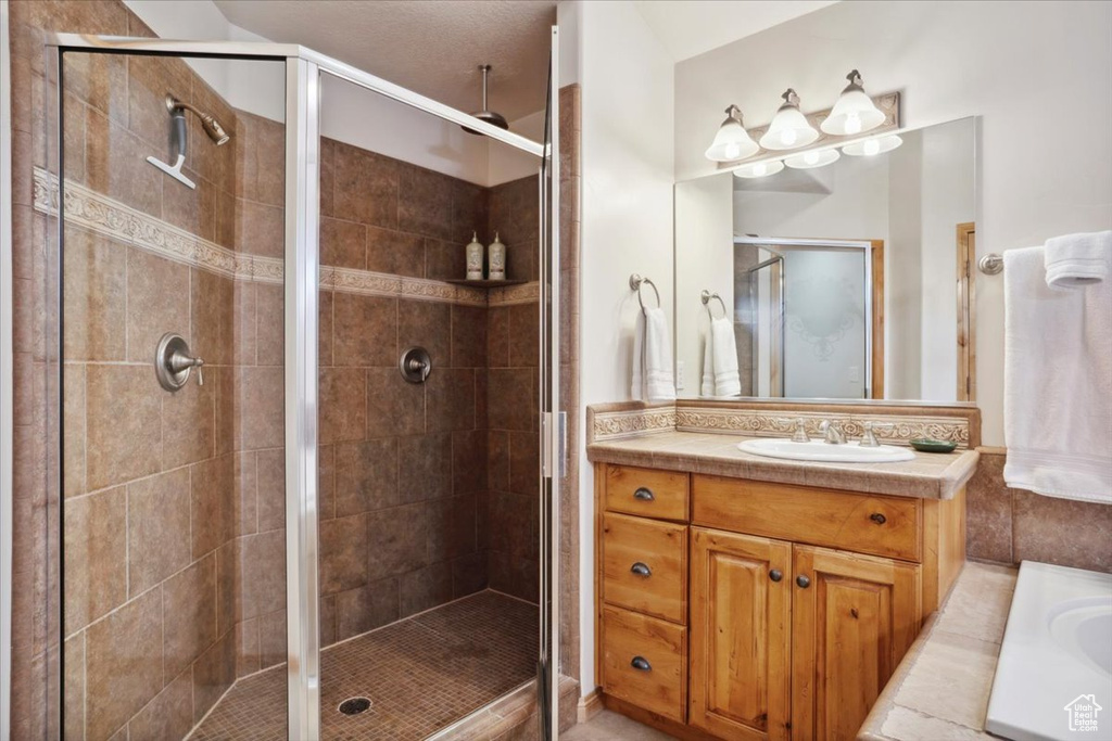 Bathroom featuring vanity, a shower stall, and a washtub