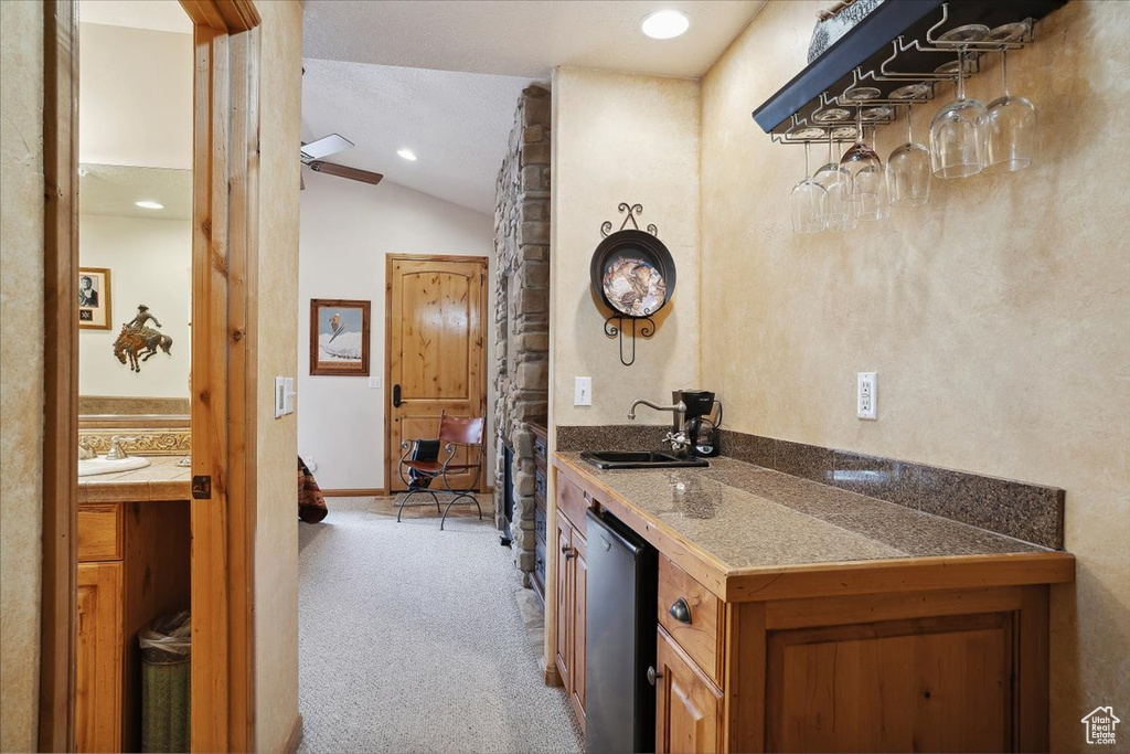 Bar with vaulted ceiling, dishwasher, carpet flooring, and a sink