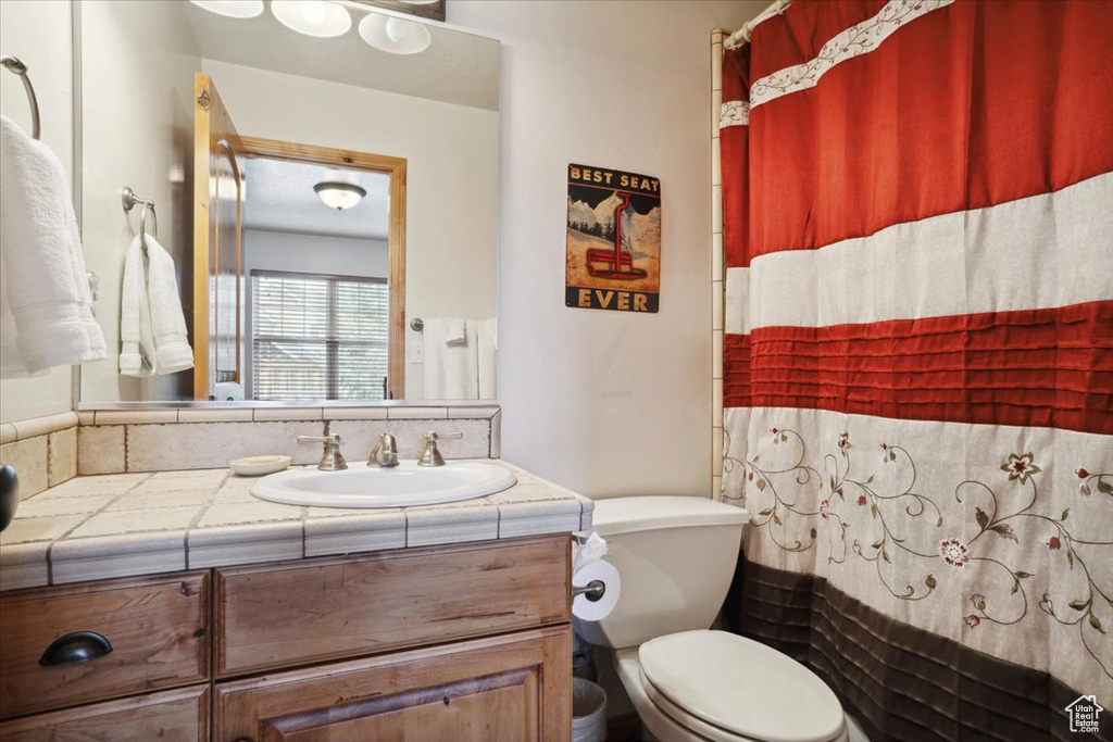 Full bath featuring curtained shower, toilet, and vanity