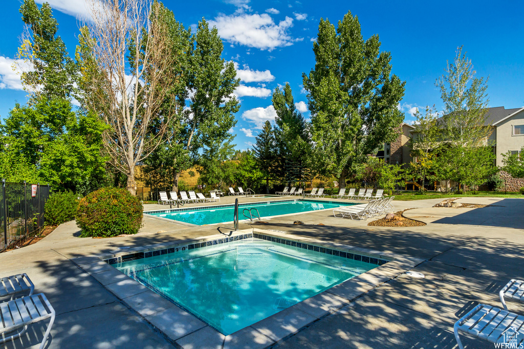 Pool featuring fence, a patio, and a hot tub