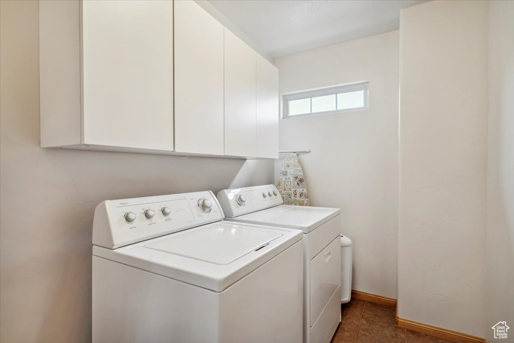 Washroom featuring washing machine and dryer, cabinet space, and baseboards