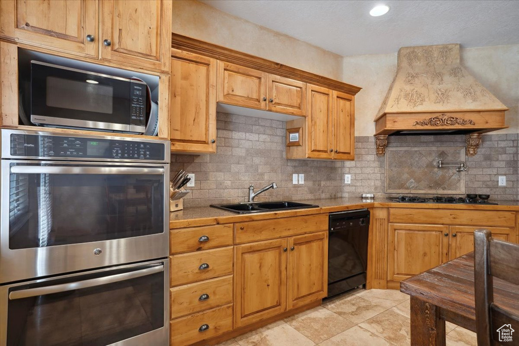 Kitchen with stainless steel double oven, custom exhaust hood, dishwasher, gas stovetop, and a sink