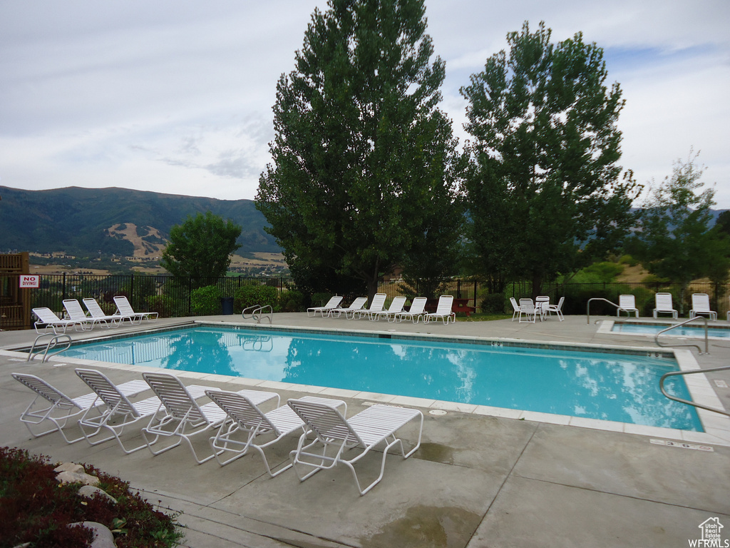 Pool featuring fence, a patio area, and a mountain view