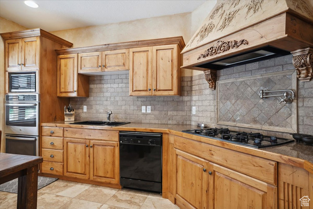 Kitchen with custom exhaust hood, appliances with stainless steel finishes, backsplash, and a sink