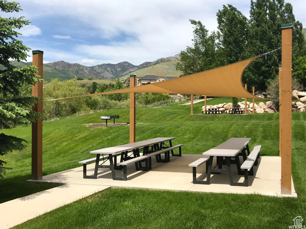 Surrounding community featuring a mountain view, outdoor dining space, a yard, and a patio area
