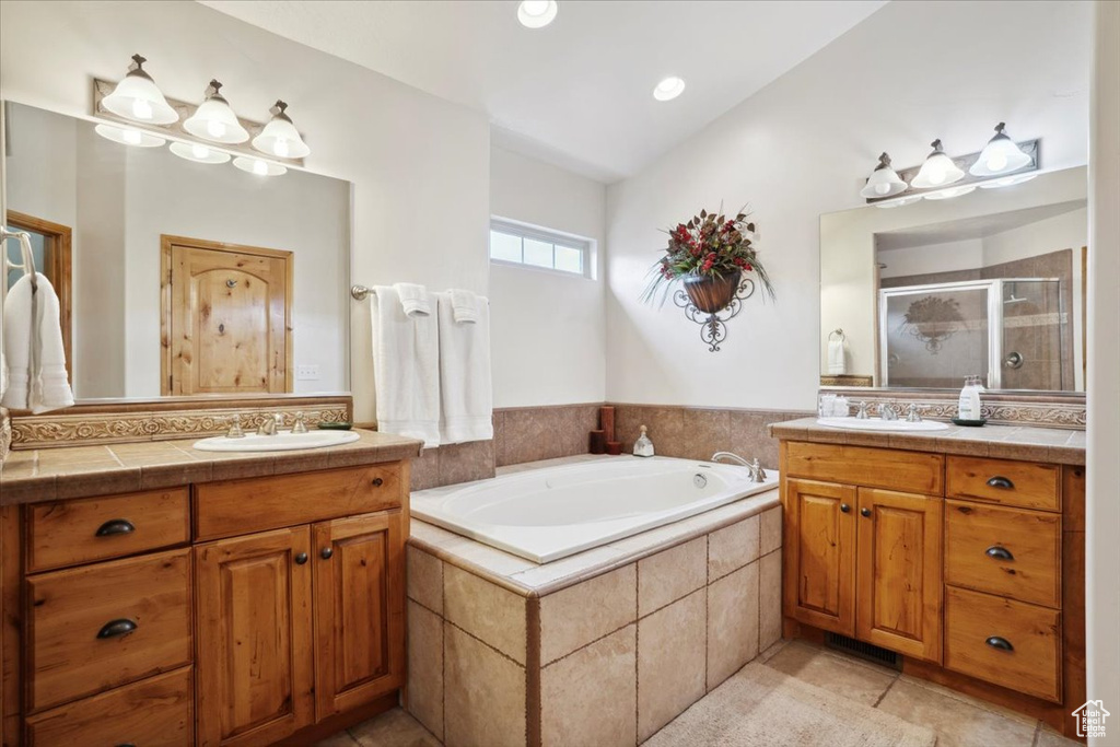 Full bath featuring two vanities, a garden tub, a stall shower, and a sink